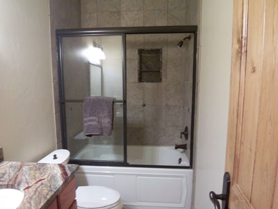 Tub slider in oil-rubbed bronze metal with towel bar attached to the metal and European header